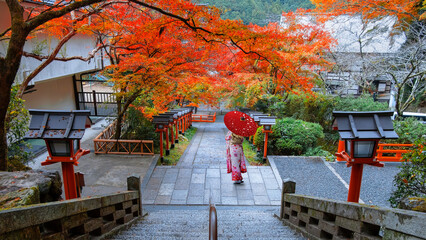 Japanese Woman in Traditional Kimono Dress at Kuramadera in a beautiful autumn scenery in Kyoto, Japan is a large temple complex spread across the side of Mt. Kurama
