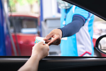 Showing a hand extending a credit card to a gas station attendant for payment. This image captures the typical scene of fuel purchase, highlighting convenience and modern payment methods at the pump.