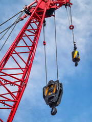 Heavy crane with pulleys lifting materials against a blue sky at a construction site