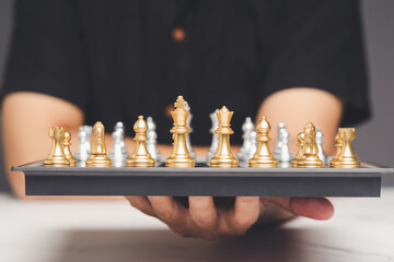 Hand presenting golden chess pieces on board, symbolizing strategy, leadership, and decision-making.