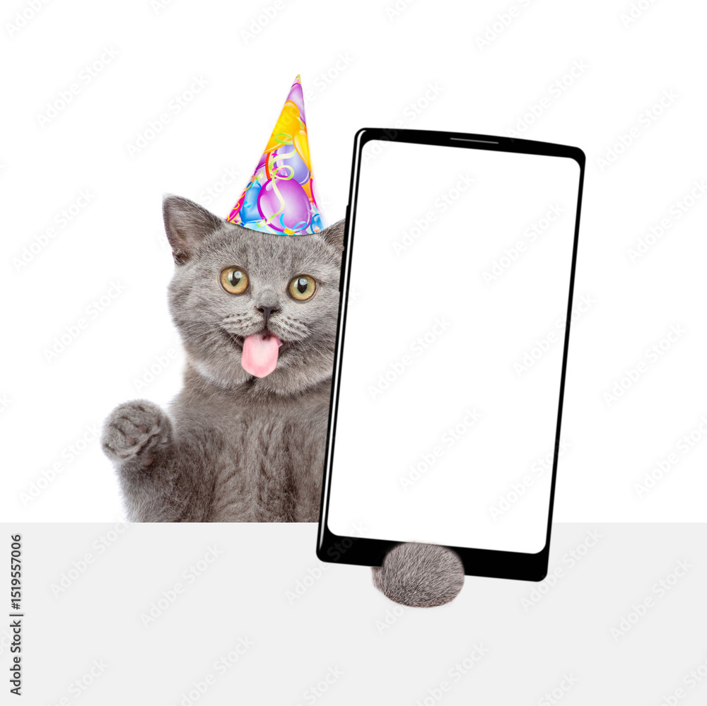 Aufkleber Happy kitten with tongue out wearing party cap shows big smartphone with blank screen above empty white banner. Empty space for text. isolated on white background