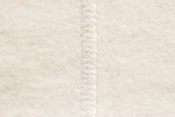 Soft beige fluffy cotton fabric with a overlock seam detail in the center texture or background © Irina
