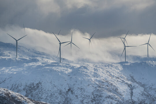 Panorama with wind park over the mountains from the island of Kval&oslash;ya, Norway, with many wind turbines. Windmills in winter on the coast of the Atlantic produce electricity.