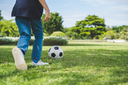 Little boy playing football in the garden with morning sunrise