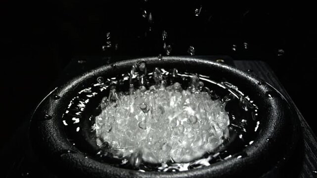 Water splashes on audio speaker. Vibrations of low bass over water in a music speaker. Black bass woofer. Subwoofer with water. The liquid jumps to the rhythm of the music at the party.