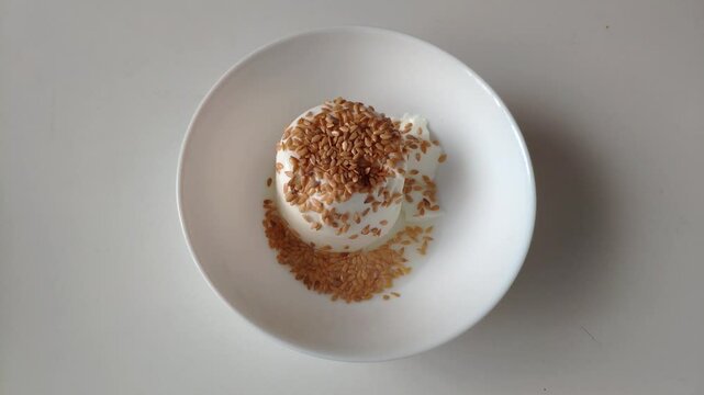 A creamy serving of junket topped with toasted sesame seeds, perfect for dessert
