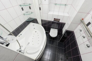 top-down view of a modern bathroom featuring a jacuzzi tub, a toilet, and tiled walls in black and...