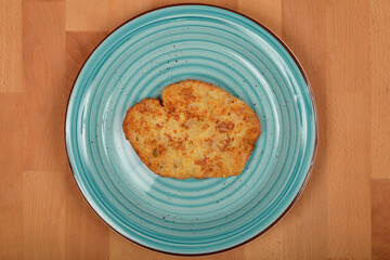 A top-down shot showcases a single piece of golden-brown fried bread, soaked in egg and fried in oil, centrally placed on a light blue, spiral-patterned plate atop a wooden surface