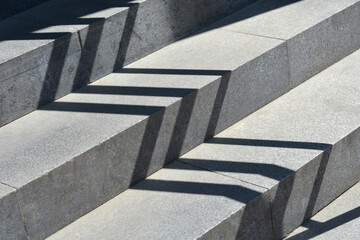 Strong geometric shadows cast by a railing create a striking diagonal pattern across a textured...