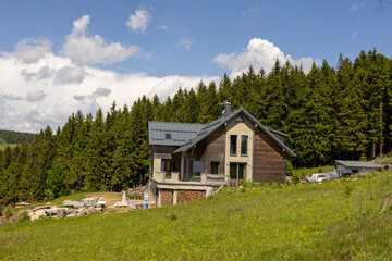 Contemporary mountain house on sunny hillside near forest