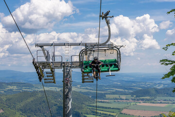Mountain biker on chairlift with scenic view of countryside and dramatic clouds