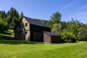 Obraz premium Old village house with red roof and green garden in quiet rural landscape