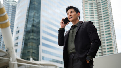 Confident businessman in a suit having a mobile conversation outdoors in a modern city.