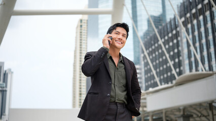 Confident businessman in a suit having a mobile conversation outdoors in a modern city.