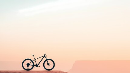 Obraz premium Silhouette of a mountain bike on a cliff edge at sunset. Concept of adventure, freedom, and outdoor activities.