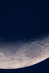 Crescent Moon features large crater floor and shadowed rim. Moonâ€™s terminator line, showcasing sharply defined craters, rugged mountain ranges and smooth lunar maria under low-angle sunlight