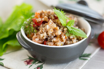 boiled buckwheat with vegetables in a ceramic bowl on a wooden table