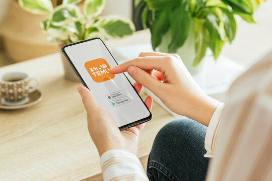 Woman installing temu app on smartphone at home