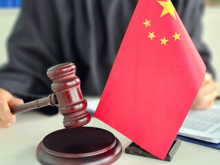China flag and gavel represent legal proceedings in a courtroom setting, underscoring the...