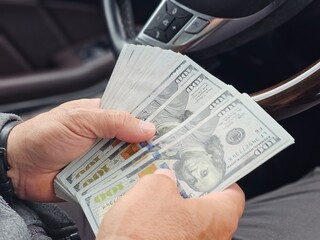 Counting cash in a car while seated in the driver seat during daytime concept
