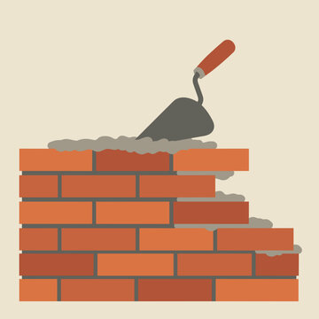 Construction worker using a trowel to lay bricks on a building site with tools nearby