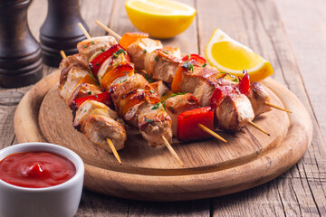 Delicious grilled chicken skewers with capsicum, lemon, salad and ketchup on a plate over the table. Chicken kebab. Healthy food concept.