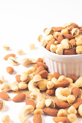 Large assortment of nuts in different bowls on stone table.