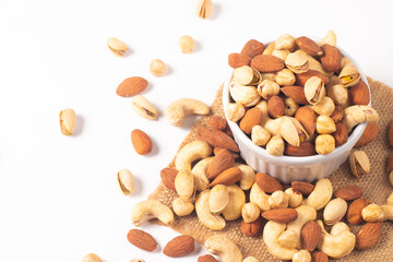 Large assortment of nuts in different bowls on stone table.