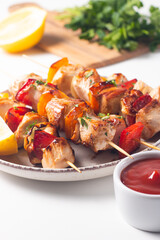 Delicious grilled chicken skewers with capsicum, lemon, salad and ketchup on a plate over the table. Chicken kebab. Healthy food concept.