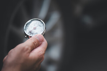Hand holding pressure gauge for car tyre pressure measurement.  (focus on pressure gauge)