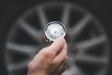 A car mechanic checks the pressure in the car's wheels. checking car wheels. Tire pressure. (focus on pressure gauge)