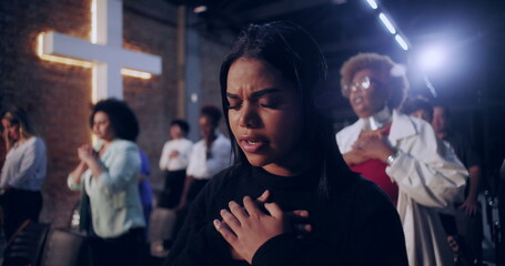 Group of women in prayer inside a church, each with hands over their hearts, expressing faith and devotion, with a glowing cross and brick wall in the background