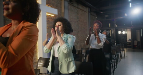 Congregation clapping hands in celebration during church service, illuminated cross and brick wall...