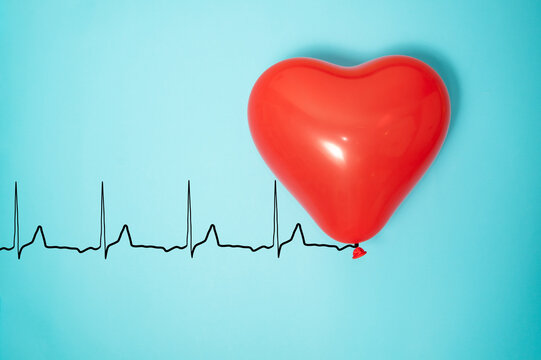 Red heart ballon with rope like a cardiogram pulse trace on light blue background.
