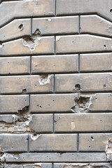 Close-up of damaged masonry with bullet and shell holes. The wall is covered with scuff marks, ideal for use as a texture or background.