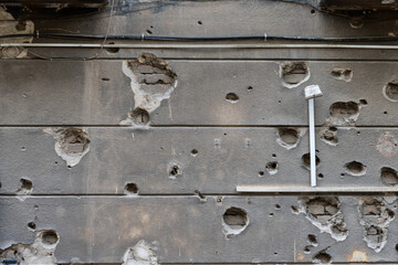 An old wall, riddled with time and bullets, creates a dramatic texture filled with hidden histories and an atmosphere of abandonment.