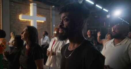 Diverse congregation raising hands in worship during church service, illuminated cross in background, spiritual connection and collective devotion in sacred space