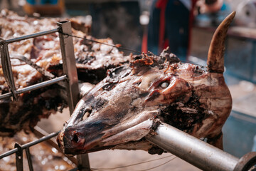 Close-up of roasted animal head on a spit, part of traditional Serbian open-fire meat preparation