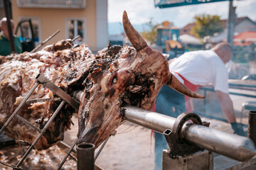 Close-up of roasted animal head on a spit, part of traditional Serbian open-fire meat preparation