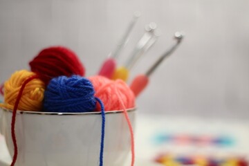 A cup and a saucer with clews balls of yarn wool and crocheted blanket handmade craft bright photo	
