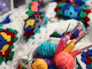 A cup and a saucer with clews balls of yarn wool and crocheted blanket handmade craft bright photo