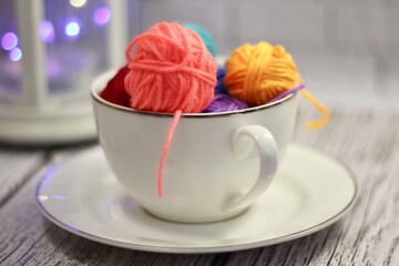 A cup and a saucer with clews balls of yarn wool and crocheted blanket handmade craft bright photo	