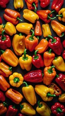 Variety of bell peppers in red, yellow, orange hues scattered across dark surface, creating vibrant contrast. Bell peppers at various angles, stages of being cut open, with seeds visible in some.