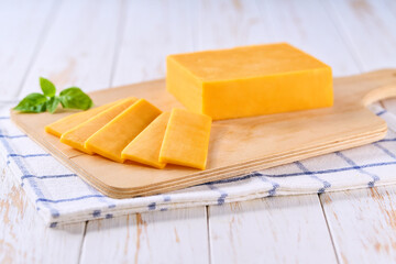 sliced natural cheese cheddar on on a white wooden table, selective focus.