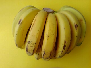 Ripe yellow bananas on a bright yellow background.
A vibrant bunch of fresh, yellow bananas.