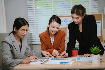 Asian business team collaborating in office, discussing strategy and project planning; professional men and women using laptop during brainstorming meeting.