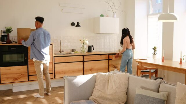 A woman removes a box from the countertop onto the floor while a woman next to him takes it out of a drawer