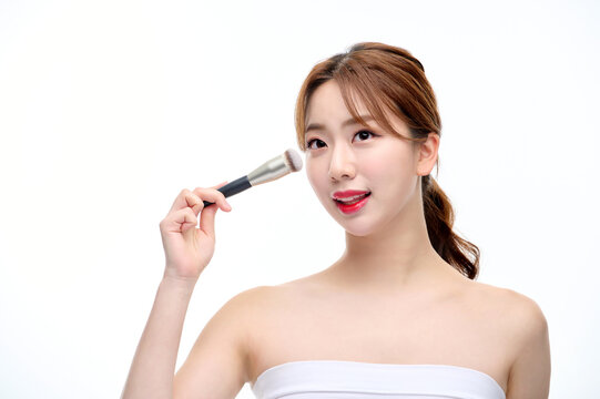 Young Woman Applying Makeup with Brush on White Background
