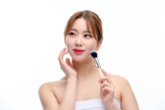 Young Woman Applying Makeup with Brush on White Background