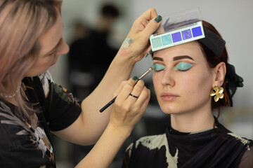 Makeup artist doing professional makeup in visage studio.